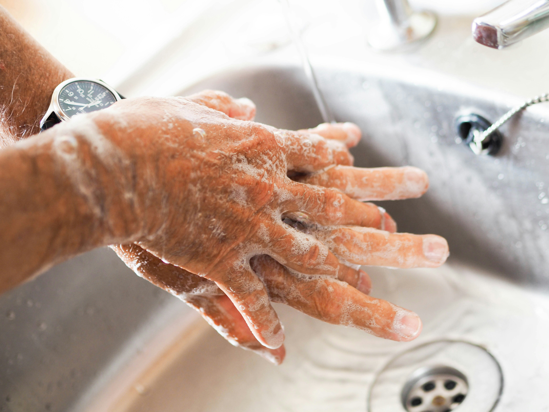Hände unter warmem Wasser mit Seife